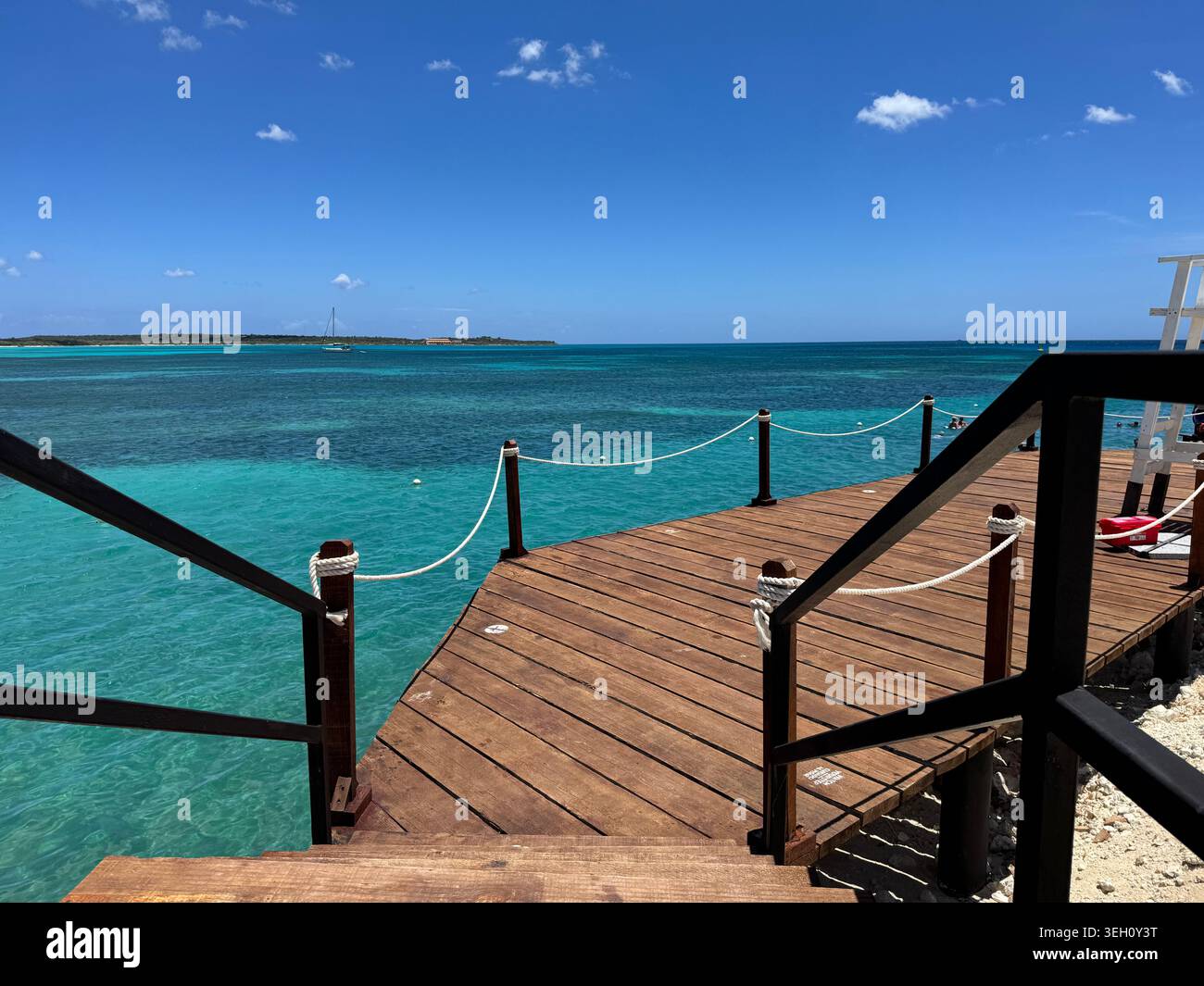 Piattaforma panoramica in legno o molo con ringhiere nere che si affacciano sulle splendide acque turchesi dell'oceano in una soleggiata giornata tropicale a CABO ROJO - Immagine stock catturata con smartphone
