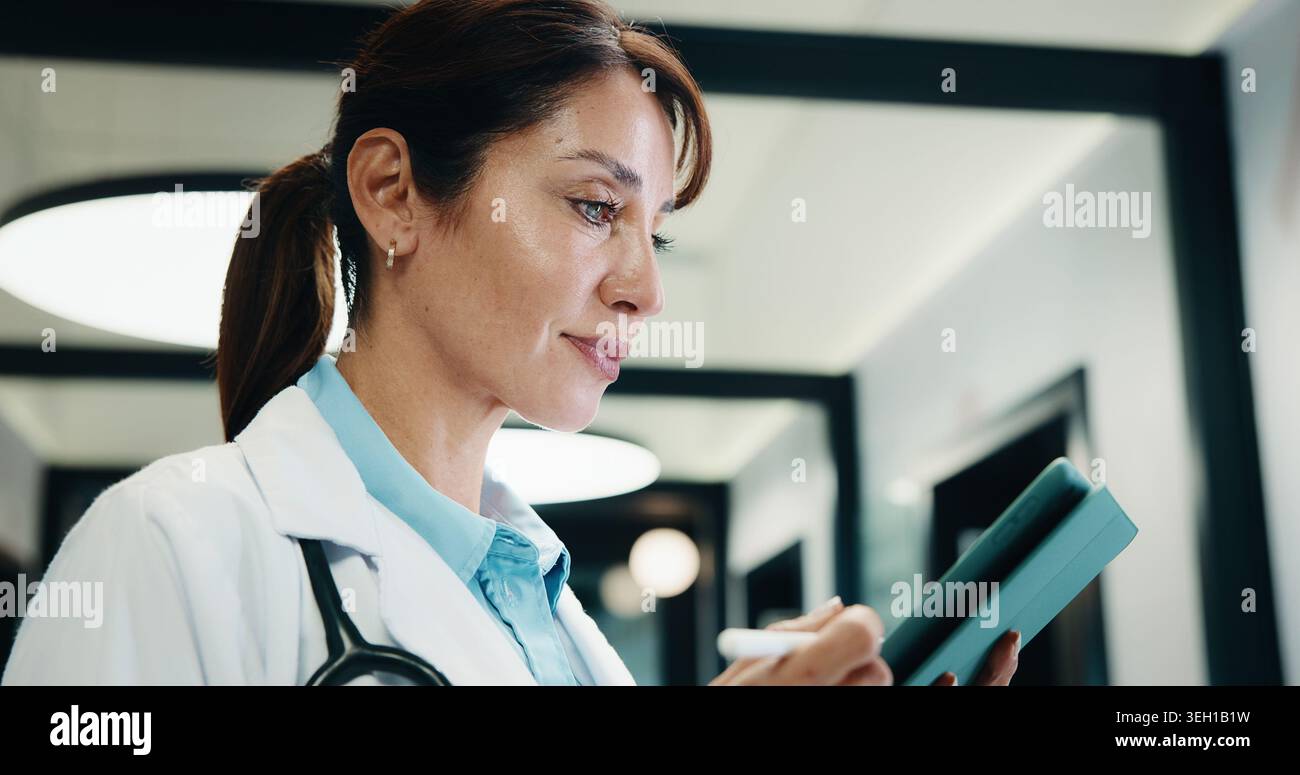 Lettura, medico e donna con compressa in ospedale, rivista medica e revisione del protocollo sanitario. Revisione, ricerca e profitto lordo maturo con eBook su Foto Stock