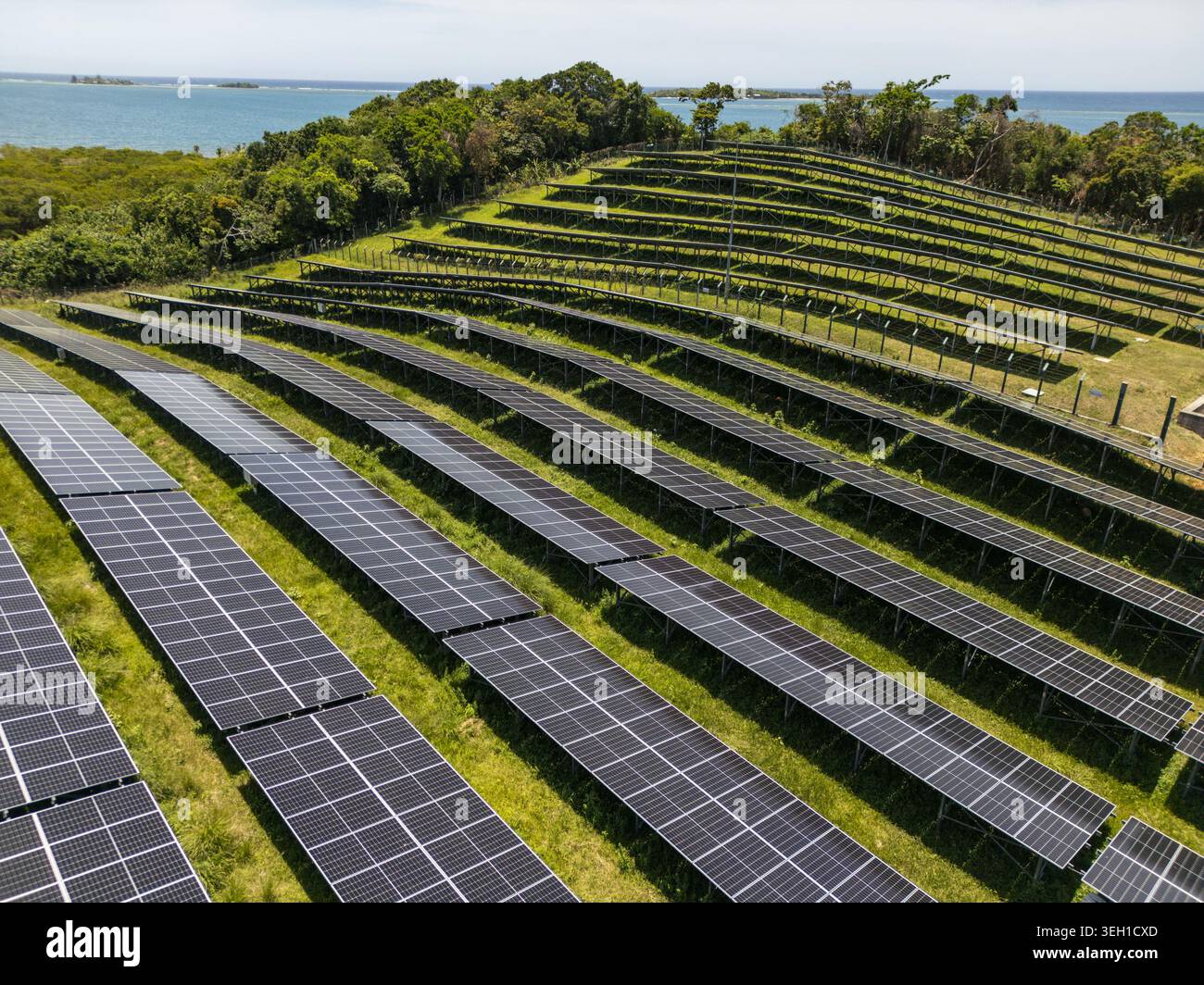 Veduta aerea di una grande fattoria a pannelli solari installata su una lussureggiante collina verde che si affaccia sul turchese Mar dei Caraibi a Guanaja, dipartimento delle isole della Baia, Foto Stock