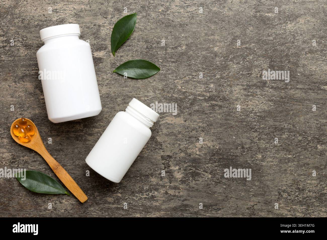 Le capsule di Omega-3 si trovano in un flacone bianco su un tavolo con il fondo verde delle foglie. Compresse di olio di pesce. Additivi biologicamente attivi omega 6, omega 9, vitam Foto Stock
