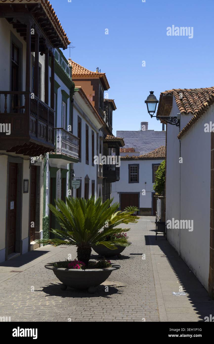 Strada stretta e vuota fiancheggiata da tradizionali balconi in legno ed edifici coloniali bianchi nella storica città di Teror, Gran Canaria. Foto Stock