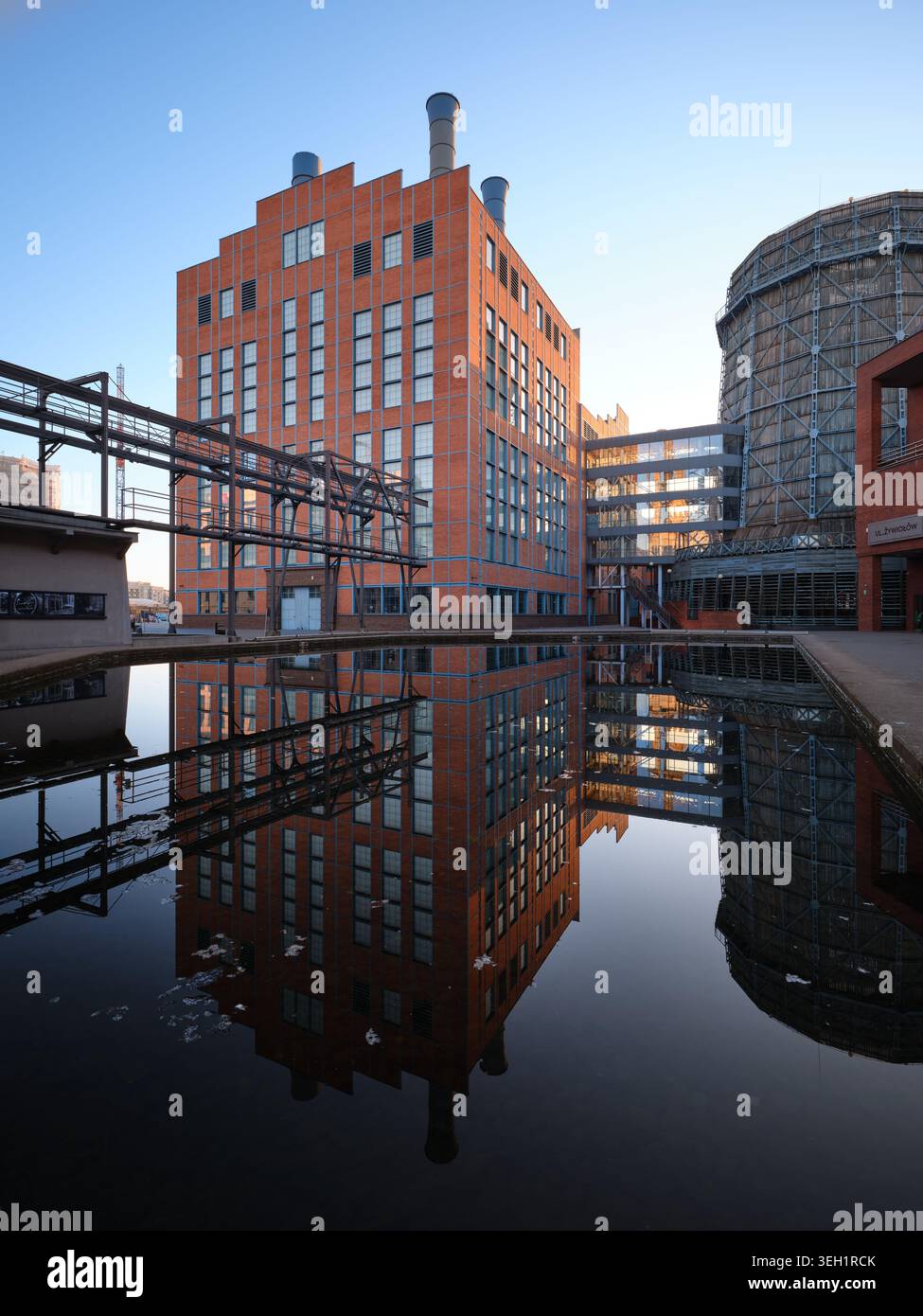 Lodz, Polonia - 12 aprile 2026: Architettura industriale EC1 riflessa nell'acqua in un complesso rivitalizzato. Foto Stock