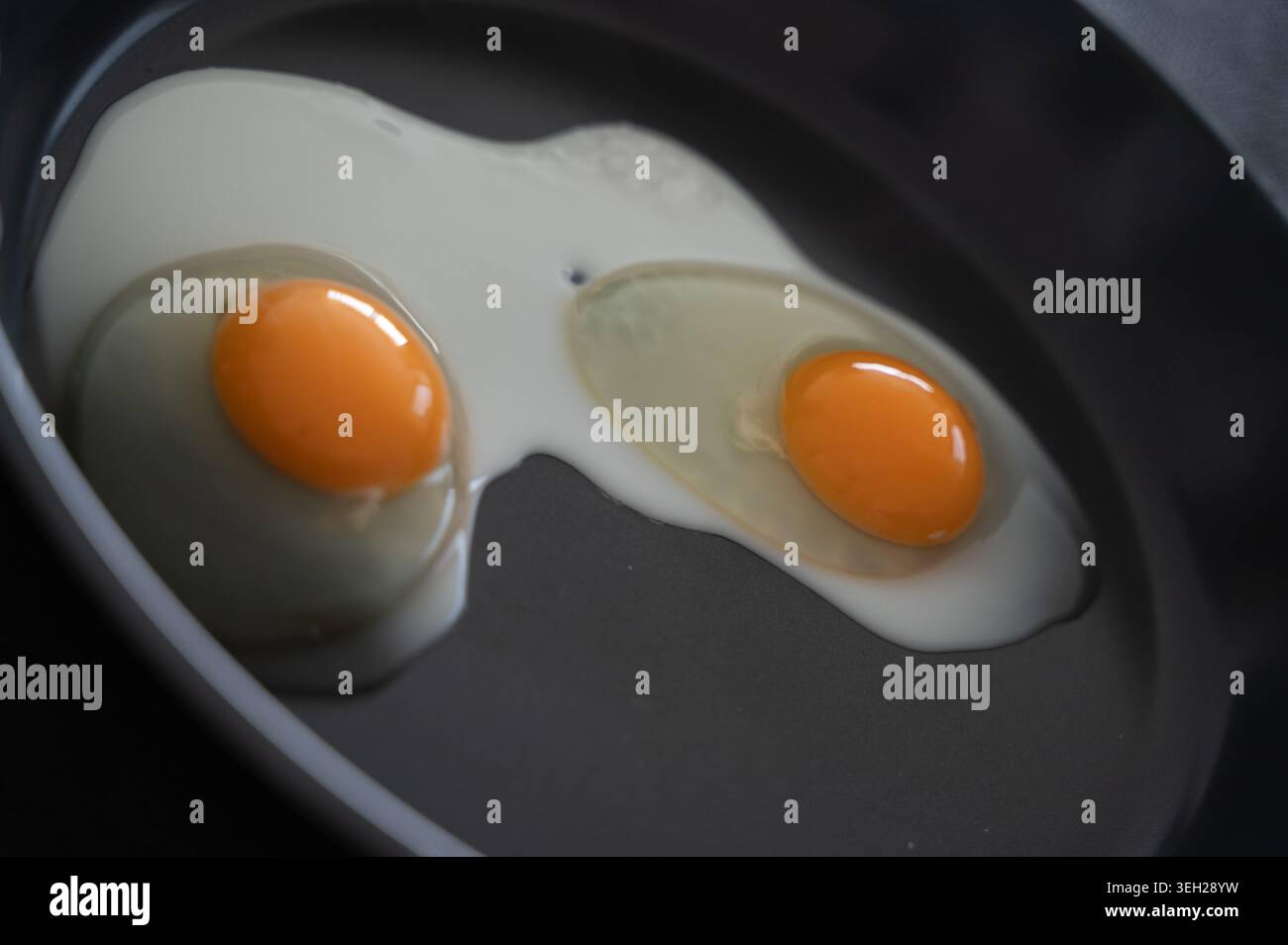 Uova aromatiche catturate da colazione con ombre tenui e un'atmosfera calda. Due uova soleggiate cotte alla perfezione con illuminazione delicata e un brunch accogliente Foto Stock