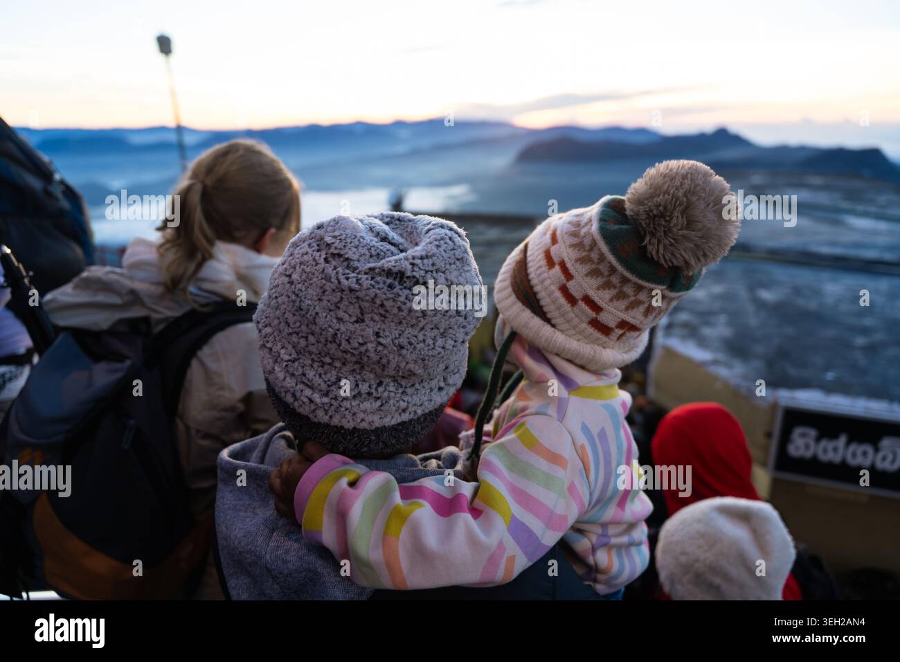 Vista di persone che indossano cappelli invernali che guardano l'alba sul paesaggio nebbioso delle montagne dal picco di Adam Ratnapura, provincia di Sabaragamuwa, Sri Lanka Foto Stock