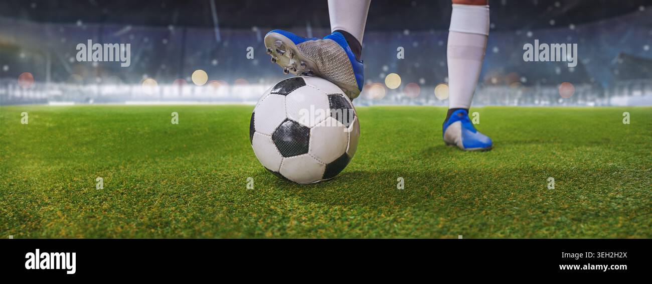 I piedi del giocatore di calcio calpestano la palla da calcio per dare il via nello stadio soleggiato. Foto Stock