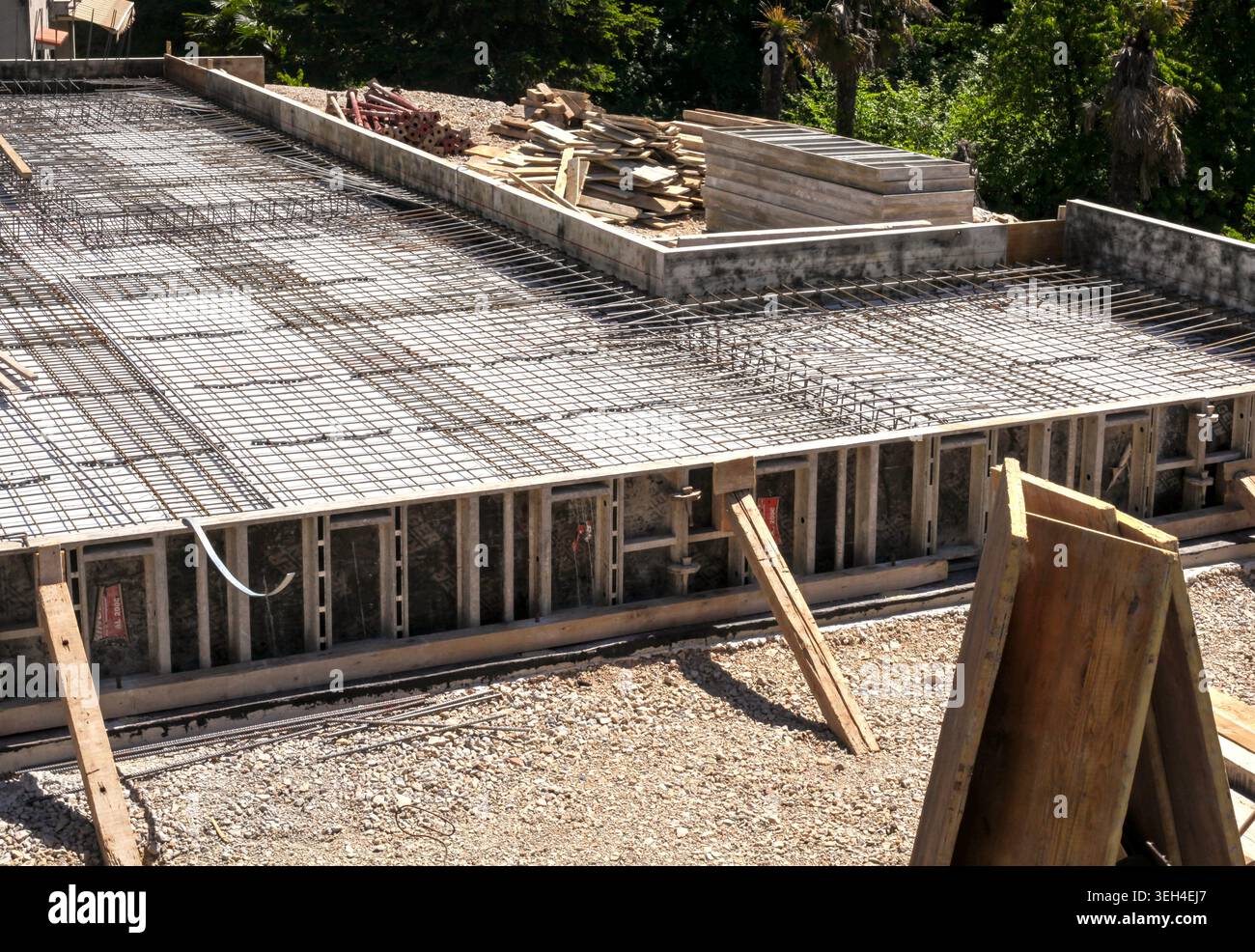 Vista ad angolo elevato di una griglia di armature in acciaio e cassaforma in legno in calcestruzzo preparata per una soletta di fondazione di edifici. Foto Stock