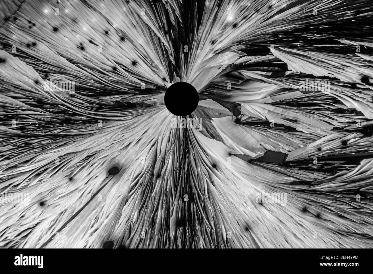 Il sale cristallizzato sotto un microscopio forma un vortice cosmico, evocando la materia che scorre in un buco nero. Foto Stock