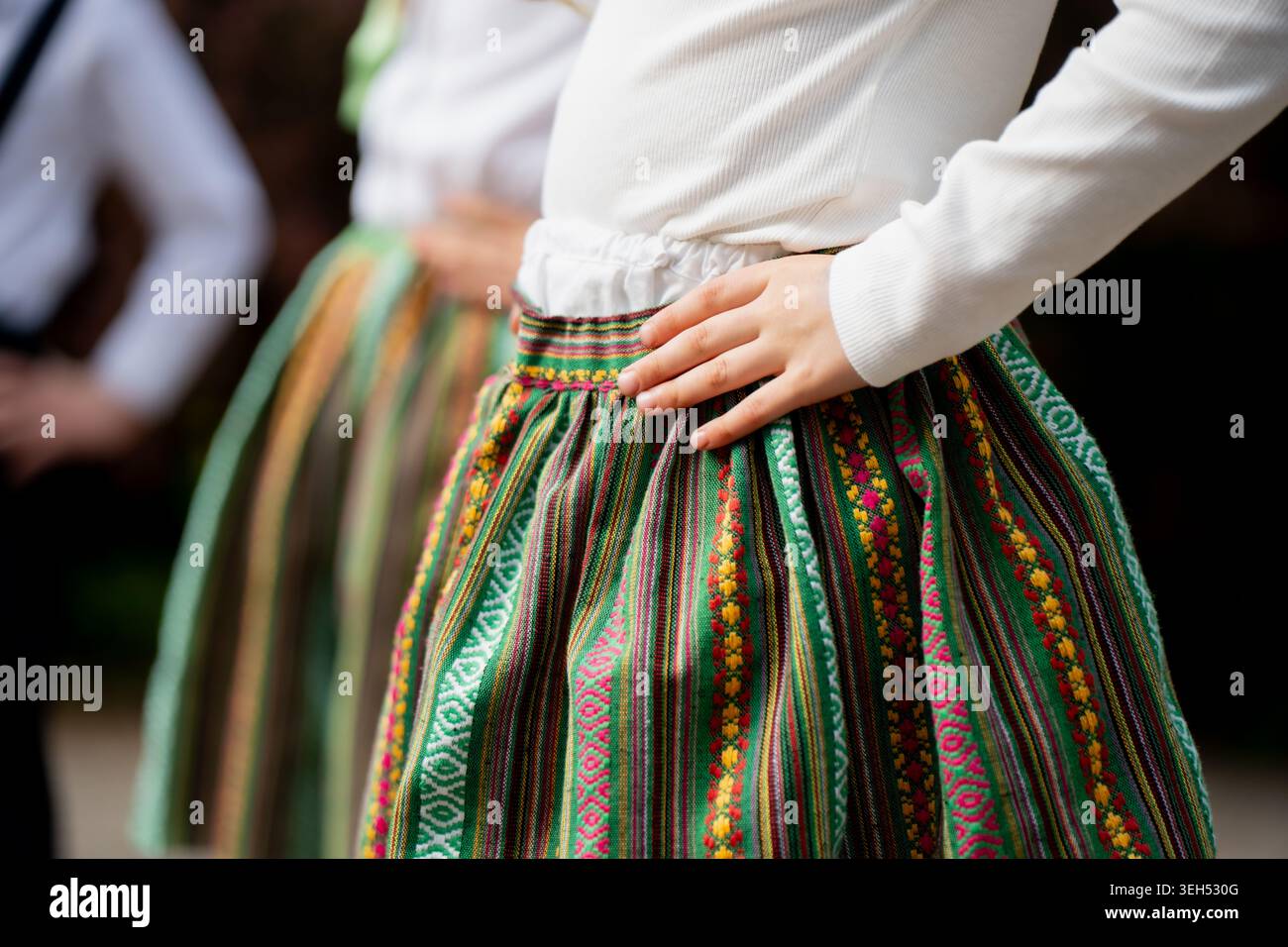 Costume da ballo folcloristico tradizionale con gonna a motivi verdi intrecciata a mano indossata dagli artisti in un evento regionale di identità nazionale Foto Stock