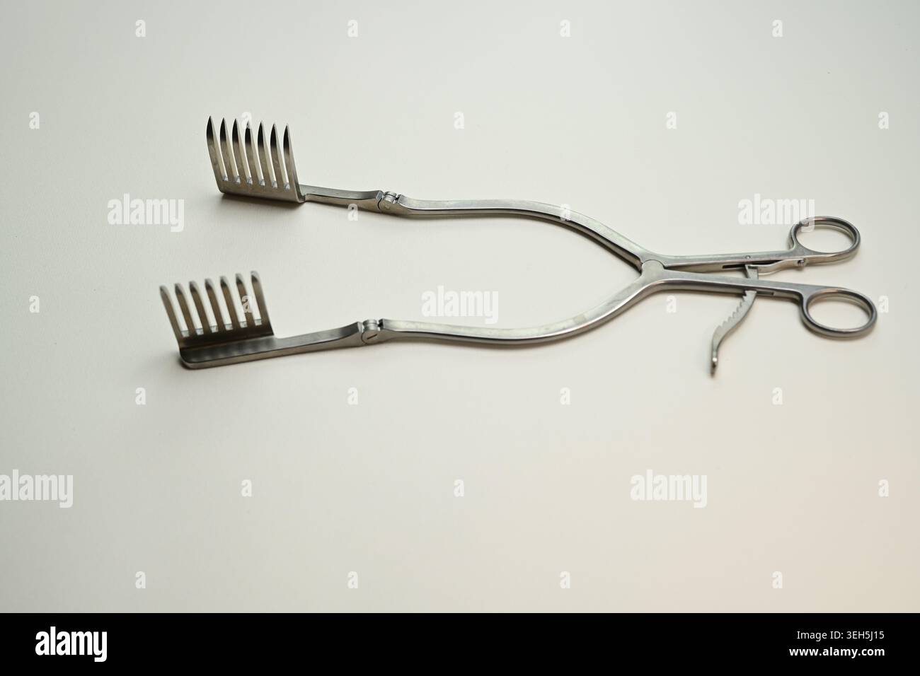 Retrattore chirurgico autoretente in acciaio inossidabile su sfondo semplice, primo piano di uno strumento operatorio per la colonna vertebrale e la neurochirurgia. Foto Stock