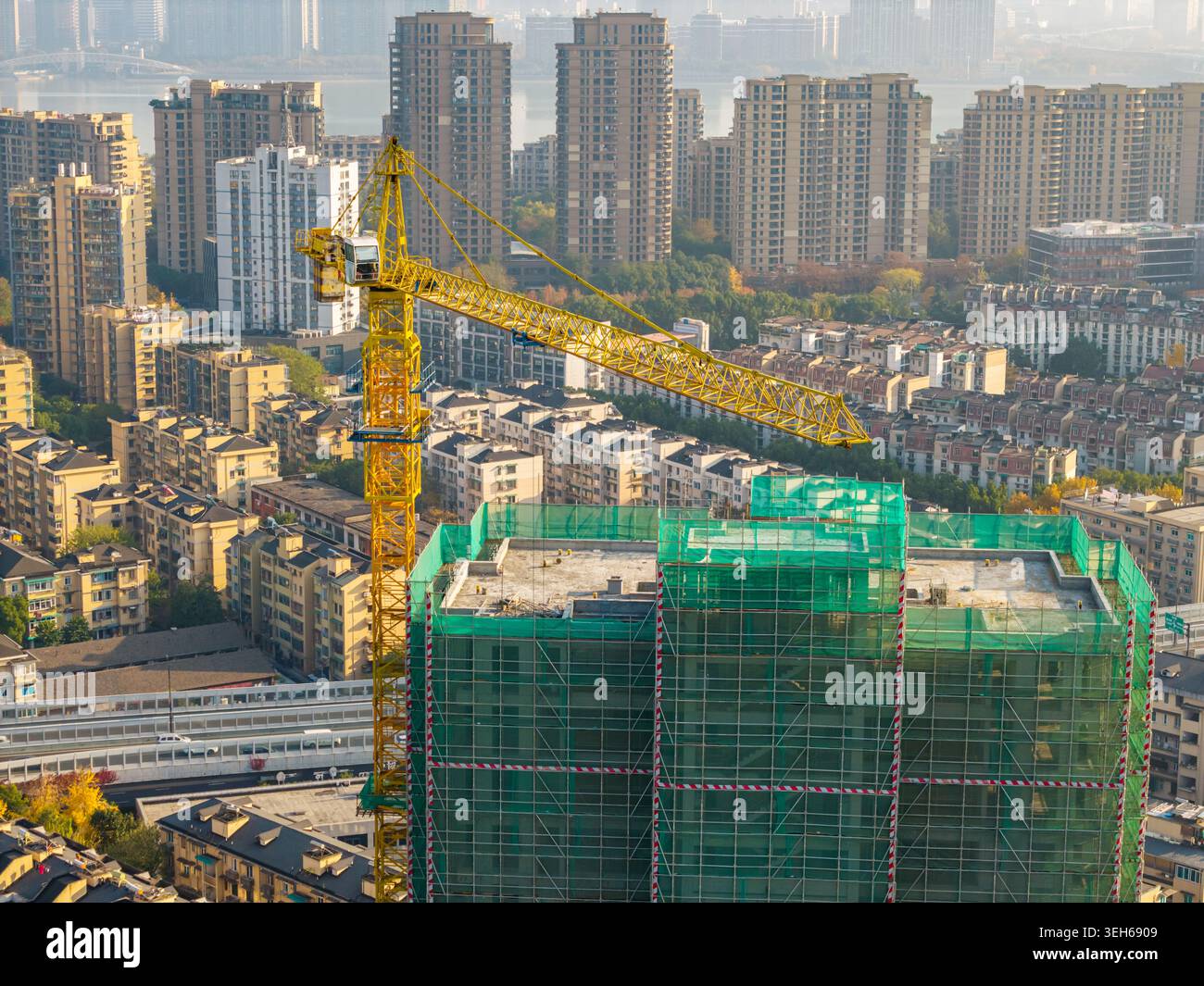 Gru a torre gialla vibrante che lavora su un progetto di costruzione in una vivace città moderna Foto Stock