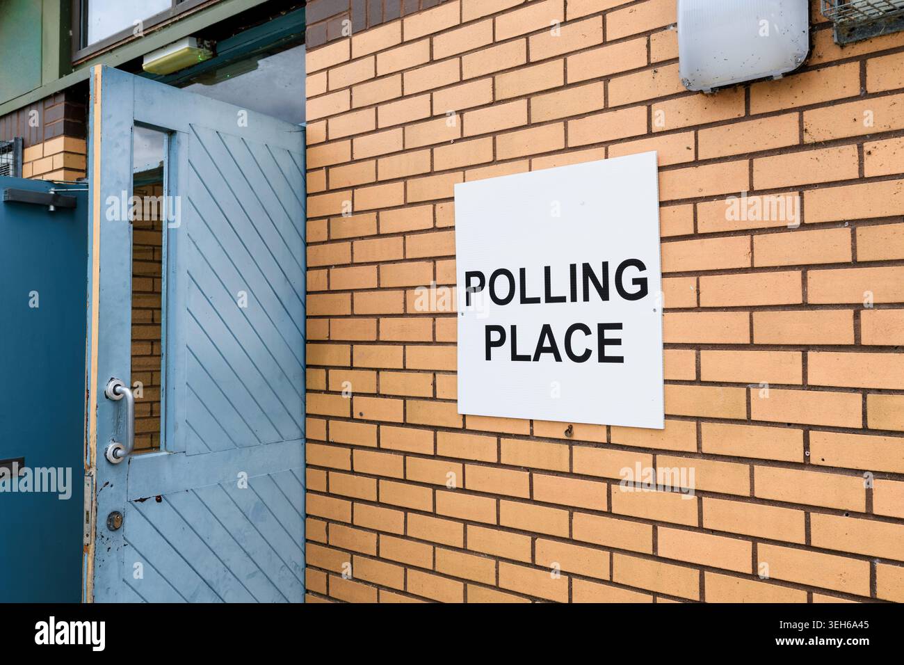 Il cartello del luogo dei sondaggi è montato su un muro di mattoni accanto a una porta aperta, che illustra l'accesso degli elettori, le informazioni elettorali e il processo democratico in Scozia Foto Stock