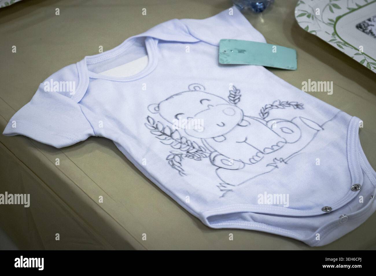 Tuta bianca per neonati con una graziosa stampa del contorno dell'orso, appoggiata su un tavolo. Indumenti morbidi per neonati preparati per la vendita, per regali o per l'uso in vivaio. Foto Stock