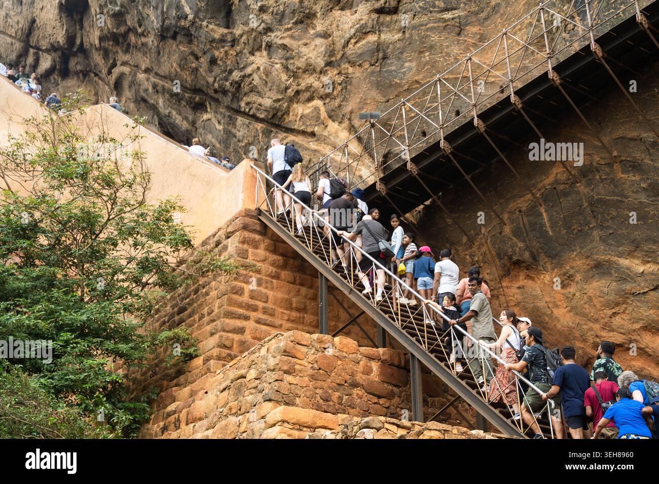 Sri Lanka - 21 febbraio 2026: Veduta dei turisti che salgono le ripide scale di metallo attaccate all'antica parete rocciosa della Fortezza di Sigiriya. Foto Stock