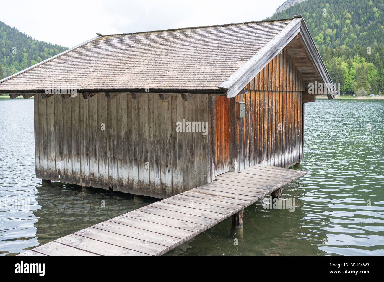 Capanna d'epoca su palafitte vicino alla riva di un bacino alpino. Concetto di solitudine, ecoturismo, destinazioni di viaggio in Europa e serenità. Foto Stock