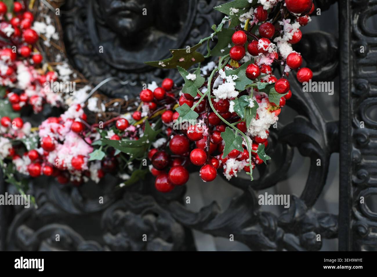 Le bacche rosse su una corona di Natale su una porta in metallo intagliato Foto Stock