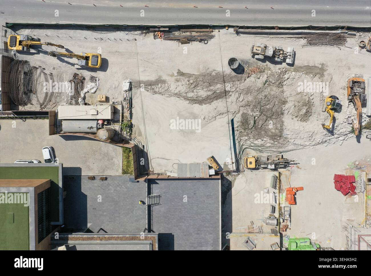 Veduta aerea di un trafficato cantiere con escavatori gialli, macchinari pesanti e mucchi di terra vicino agli edifici urbani Sariyer, Istanbul, Turkiye. Foto Stock