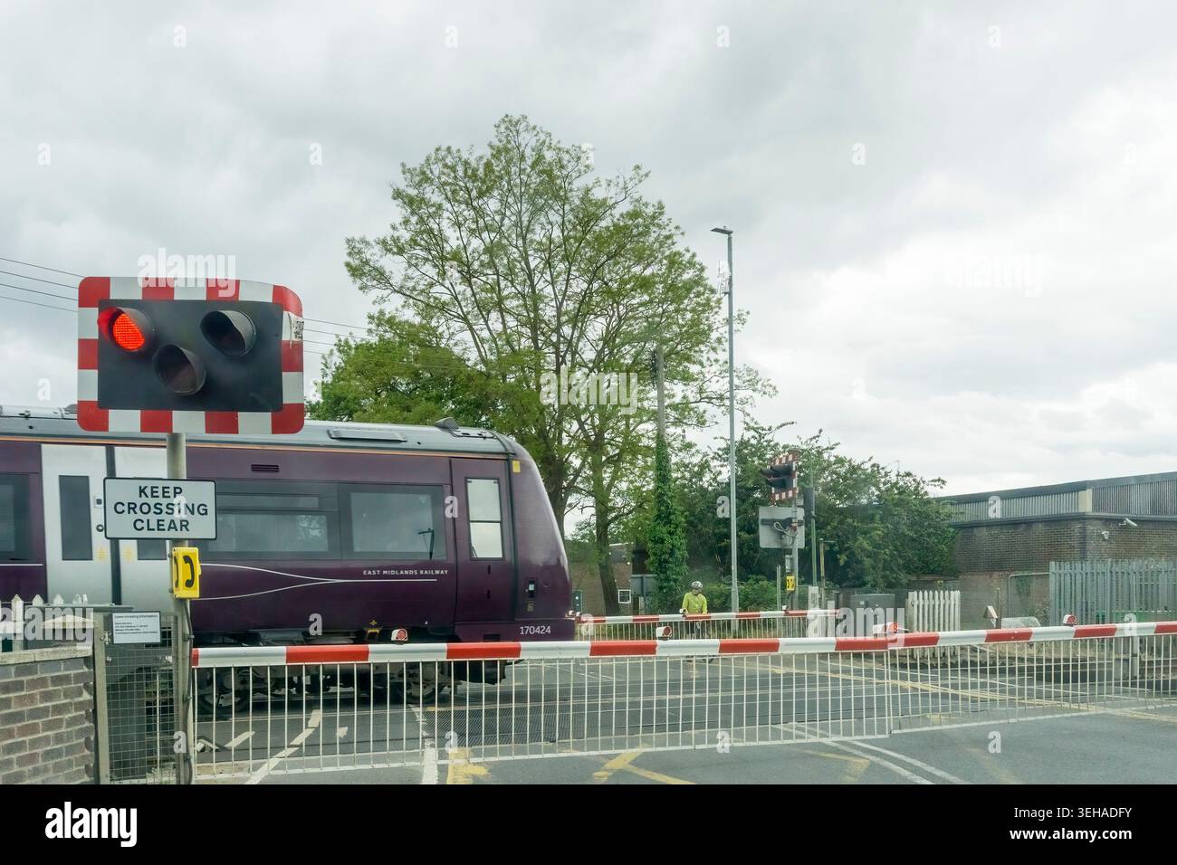 Un treno passeggeri della East Midlands Railway che attraversa la strada A1065 sul passaggio a livello a Brandon, Suffolk. Foto Stock
