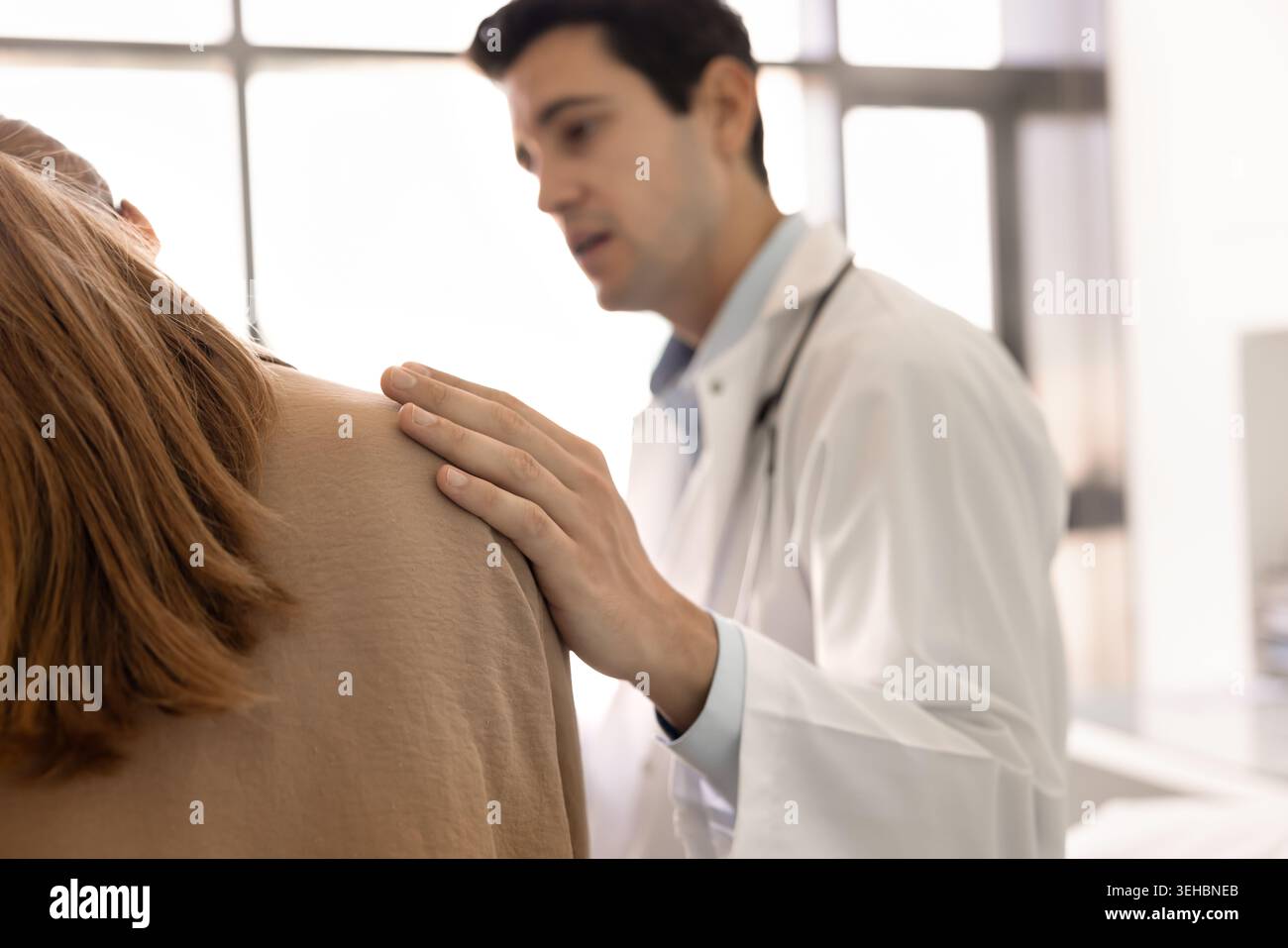 Primo piano del medico che posiziona delicatamente la mano sulla spalla della paziente Foto Stock