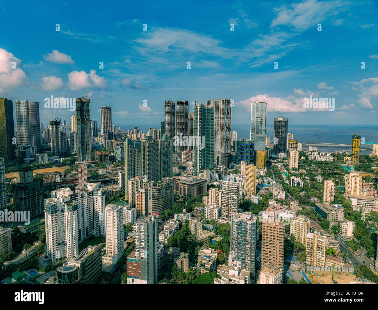 Mumbai, India - 17 maggio 2026: Veduta aerea del denso skyline urbano di Mumbai con moderni grattacieli, torri residenziali e lussureggiante vegetazione unde Foto Stock