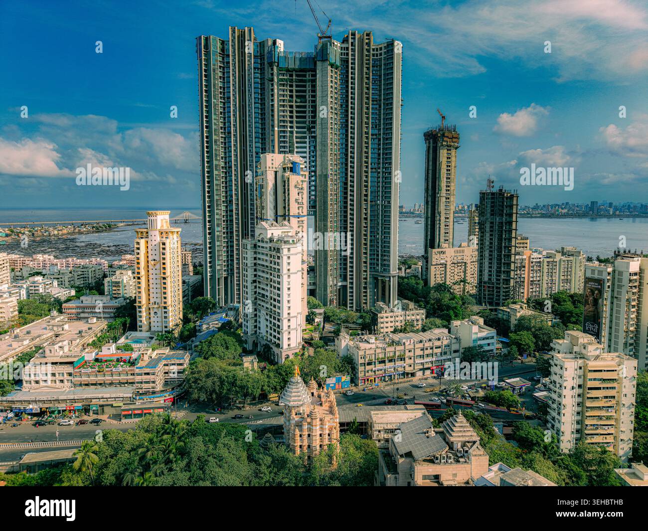 Mumbai, India - 17 maggio 2026: Veduta aerea dei moderni grattacieli e di un tempio tradizionale nel denso paesaggio urbano di Mumbai con la costa Foto Stock