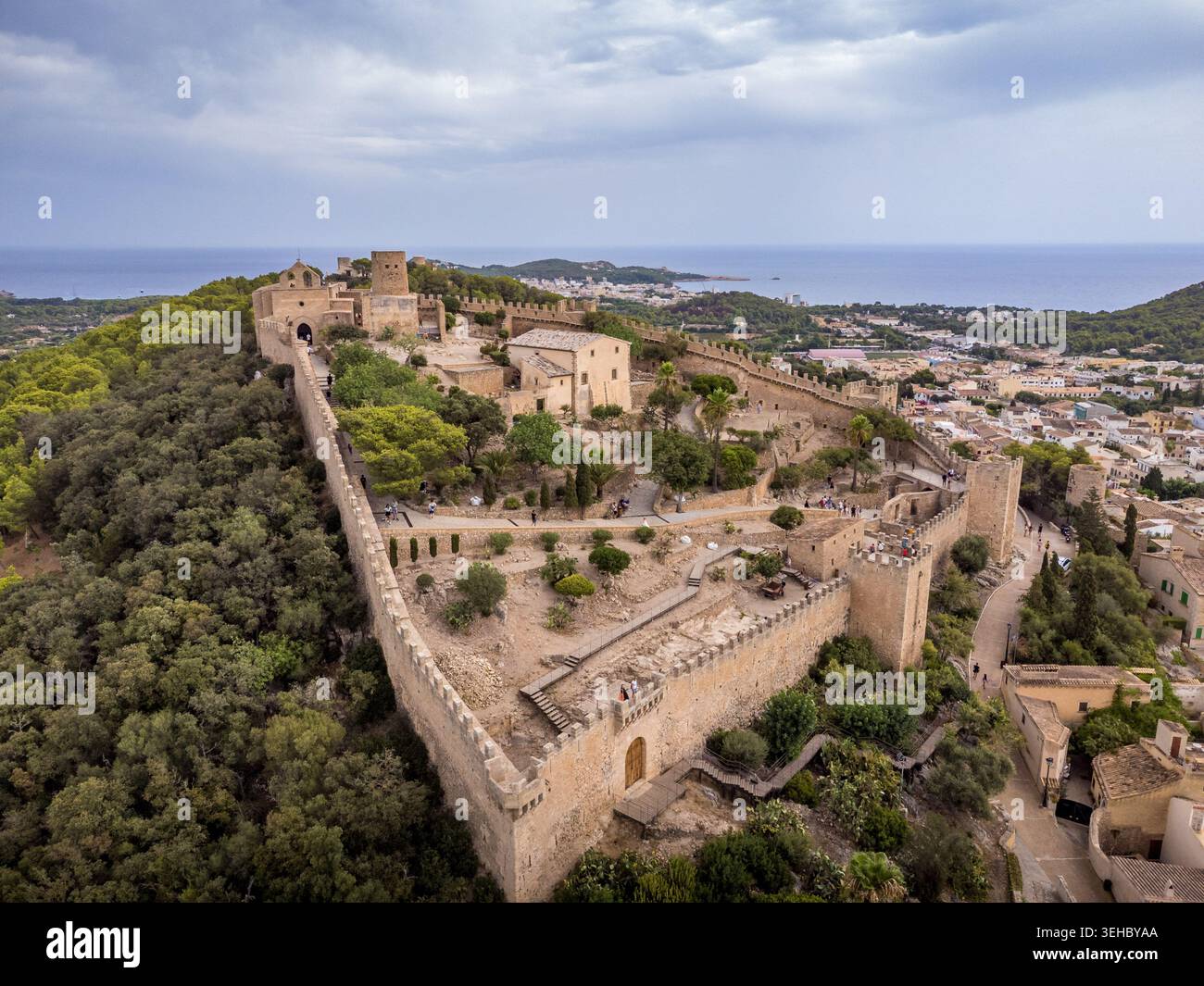Veduta aerea del castello di Capdepera ben conservato, con merlature e torri che si affacciano sulla città costiera e sul blu del Mediterraneo Foto Stock