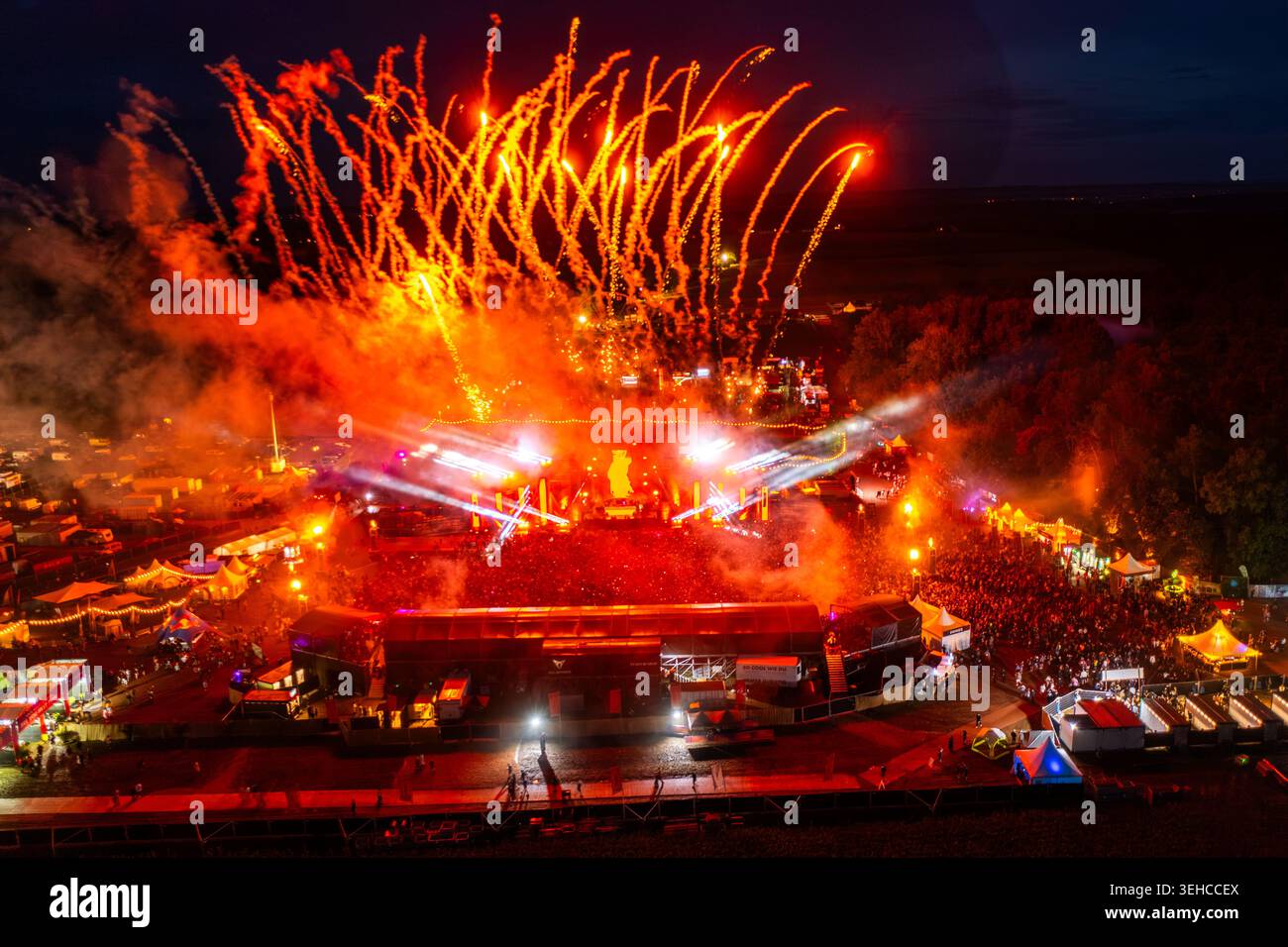Herzogenaurach, Germania - 24 luglio 2025: Veduta aerea dell'Open Beatz Festival con vivaci fuochi d'artificio che esplodono sopra una grande folla e la sala illuminata Foto Stock