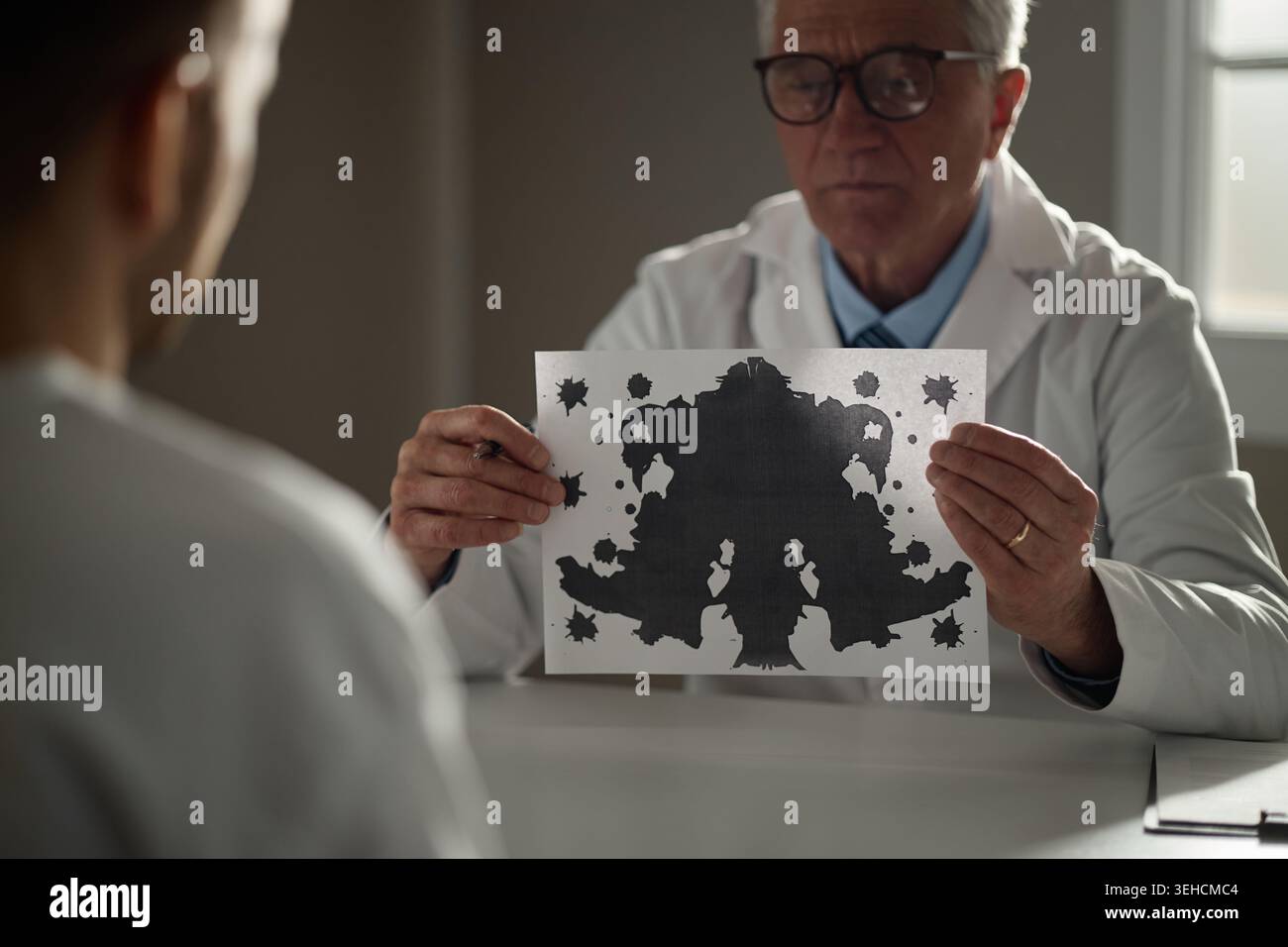 Senior maschio terapista che mostra il test di Inkblot durante la sessione di salute mentale Foto Stock