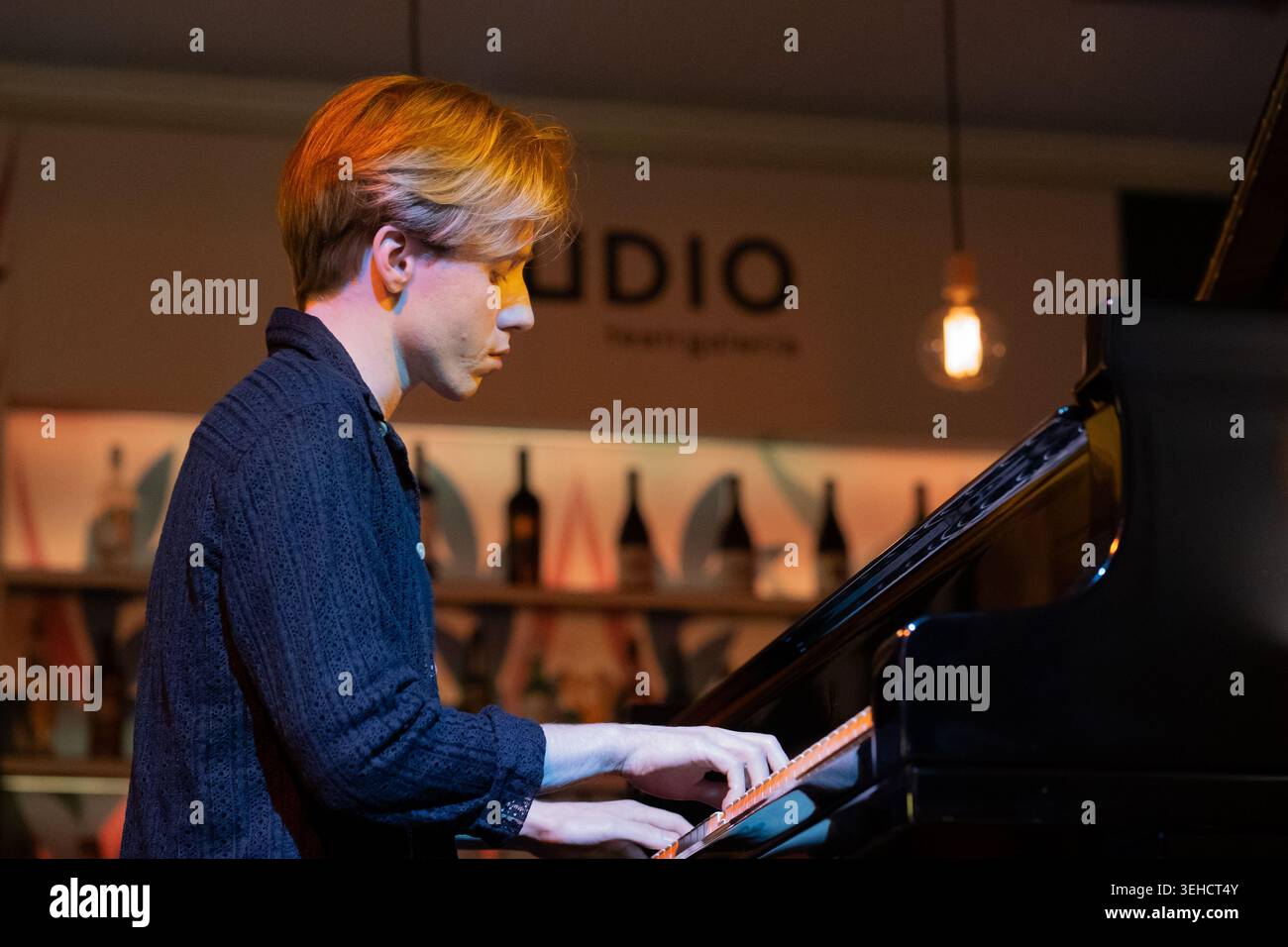 Julius Asal si esibisce al barStudio di Teatr Studio, Varsavia, con bottiglie visibili sullo sfondo, creando un'atmosfera da concerto informale e unica. Foto Stock