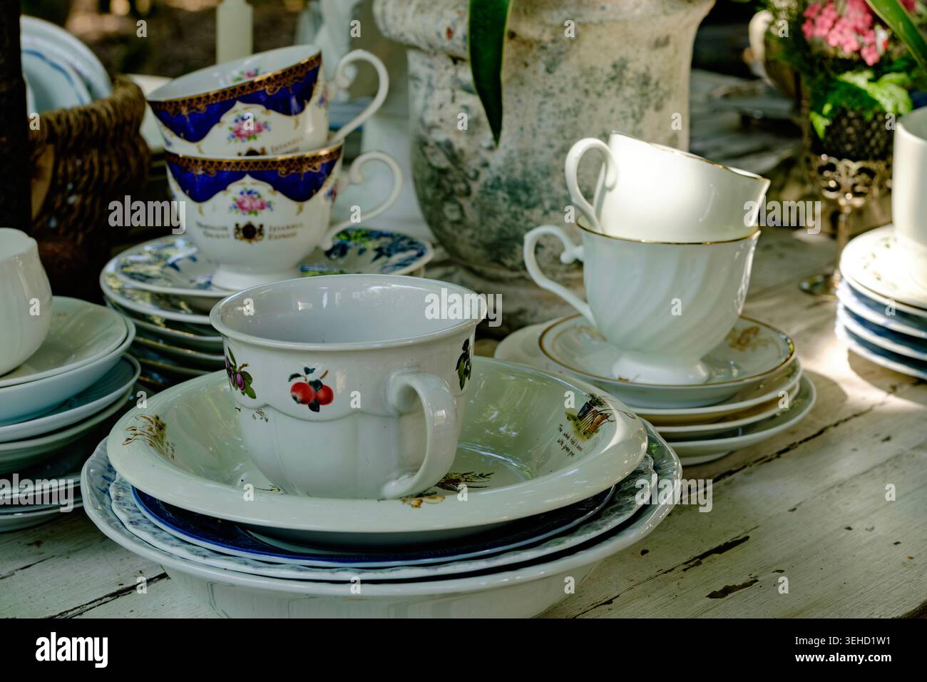Una collezione di bellissime tazze e piattini da tè in porcellana antica esposti su un tavolo rustico in un mercato vintage Foto Stock