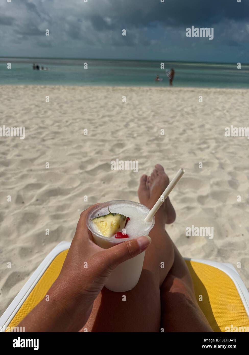 pina colada in mano a una donna sul lettino ai caraibi - Immagine stock catturata con smartphone