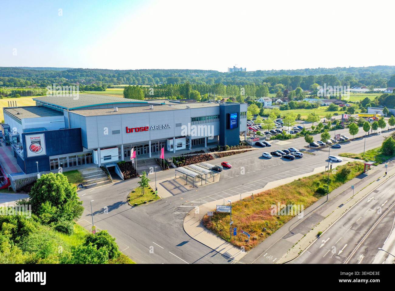 Bamberga, Germania - 2 maggio 2026: Veduta aerea della Brose Arena, con la sua facciata moderna, l'area parcheggio e i lussureggianti dintorni verdi sotto un chiaro chiaro e luminoso Foto Stock