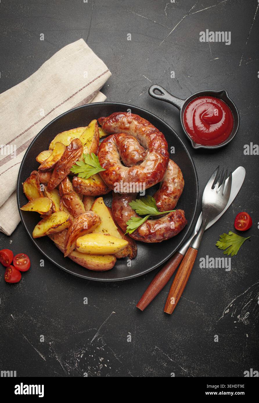 Involtini di salsiccia con spicchi di patate e ketchup Foto Stock