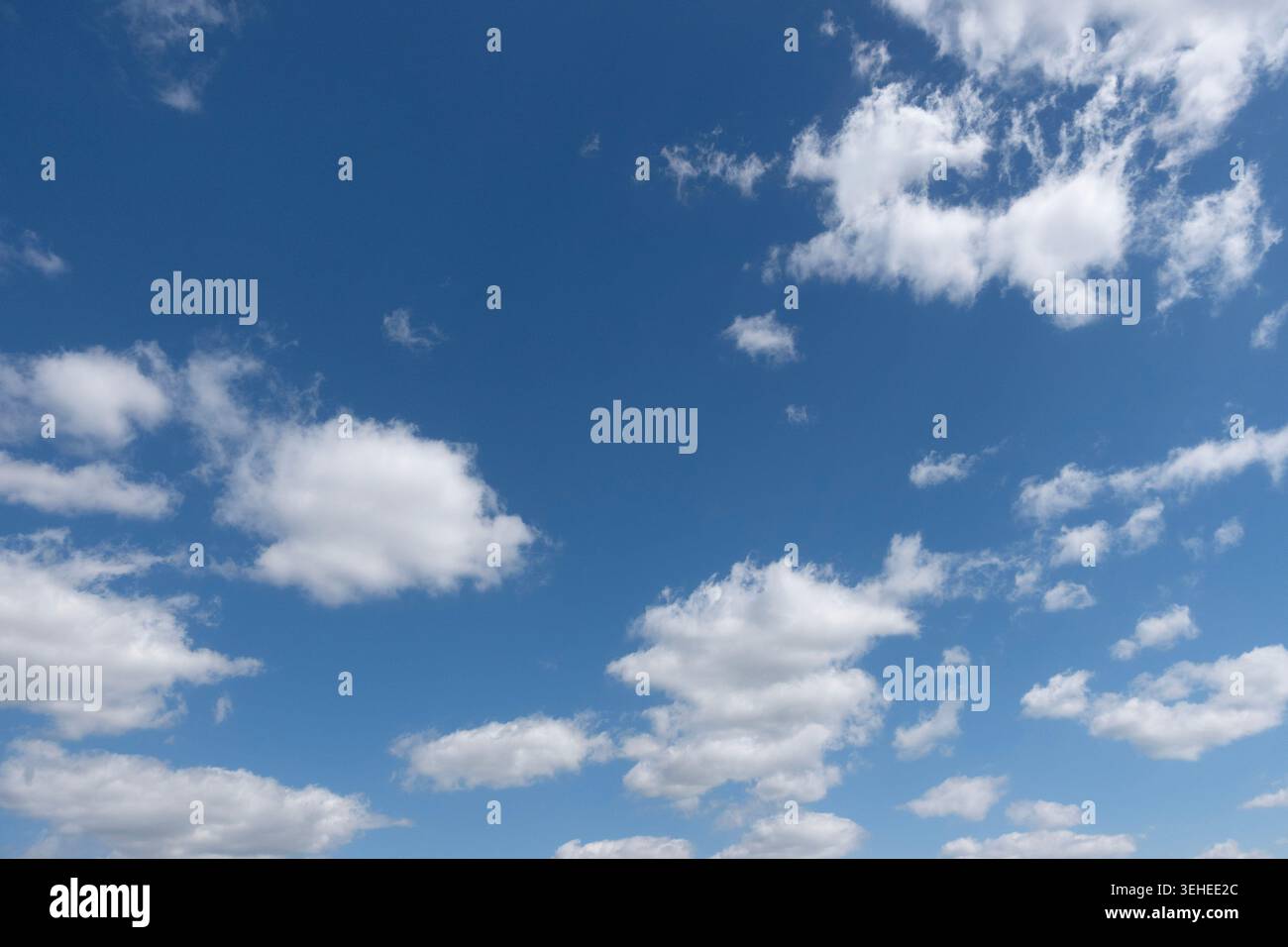 Ampio cielo blu con nuvole bianche di cumulus sparse, clima estivo pulito e spazio per copie dall'atmosfera suggestiva Foto Stock