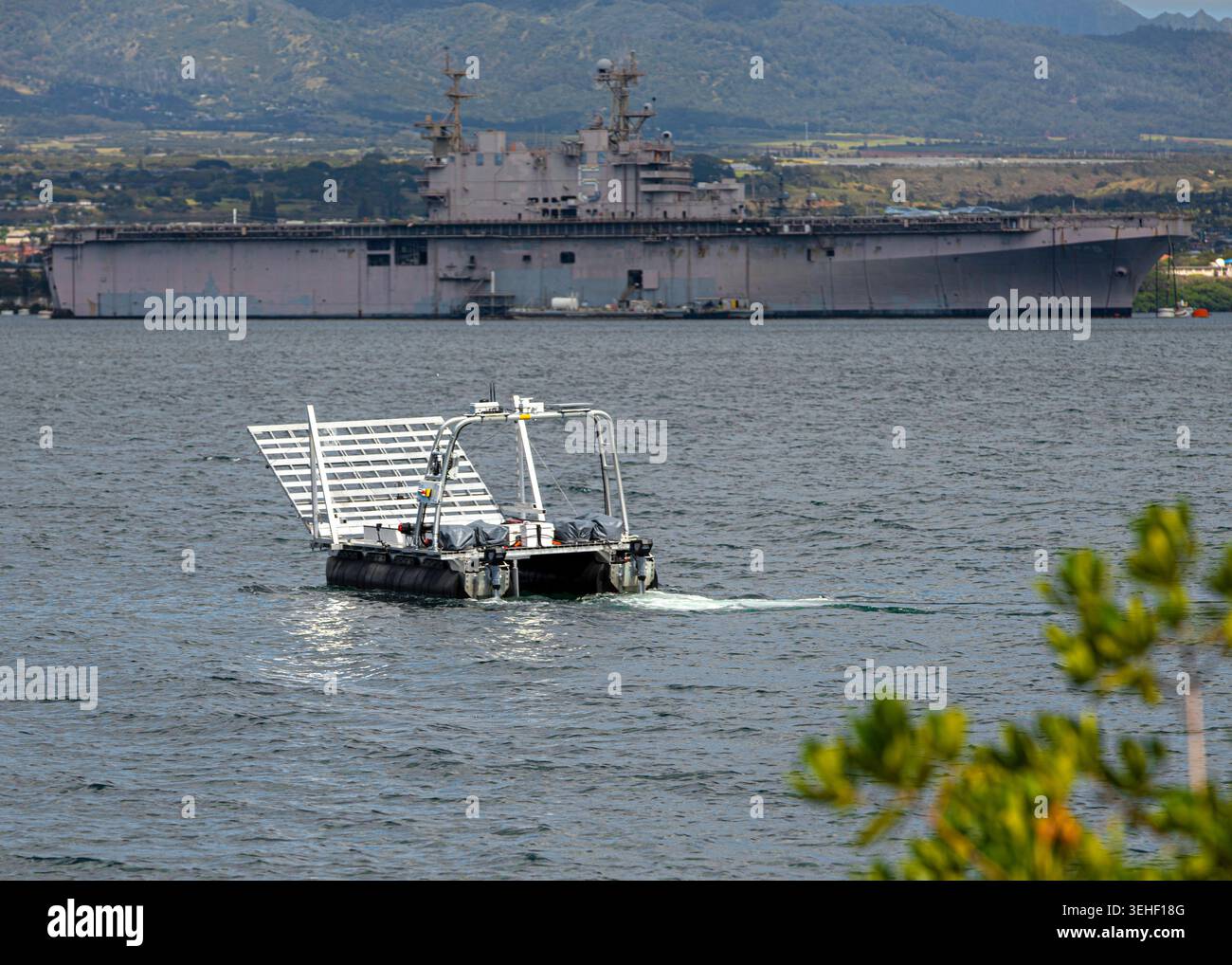 Una nave di superficie senza equipaggio (USV) si muove attraverso l'acqua con la USS Peleliu sullo sfondo durante una prova per il progetto Convergence - Capst Foto Stock