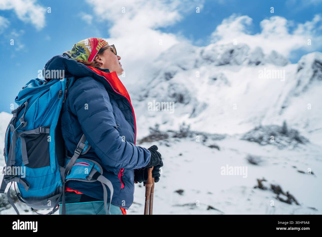 Trekker sorridente con zaino grande e bastoncini da trekking a fuoco con lo sguardo verso la montagna sfocata di Eisenerzer Reichenstein in Austria riprende Foto Stock
