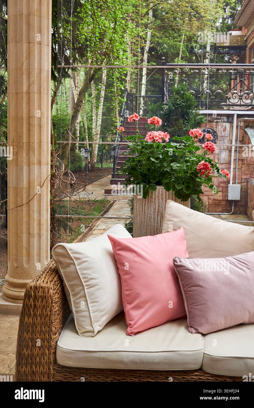 Accogliente lounge Corner Luxury con divano in vimini e cuscini rosa Foto Stock