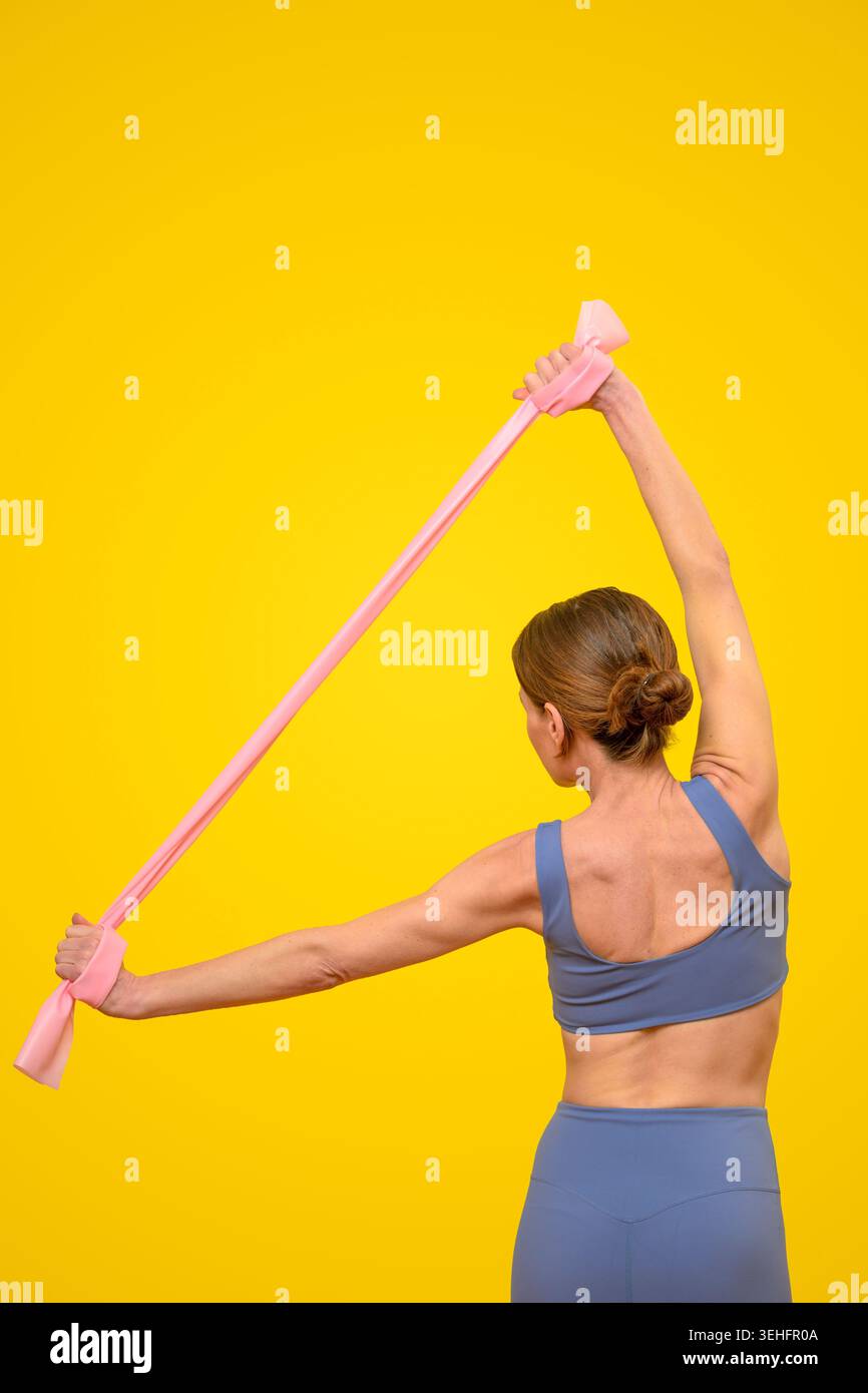 Fit donna che si allunga con fascia di resistenza sopra la testa Foto Stock