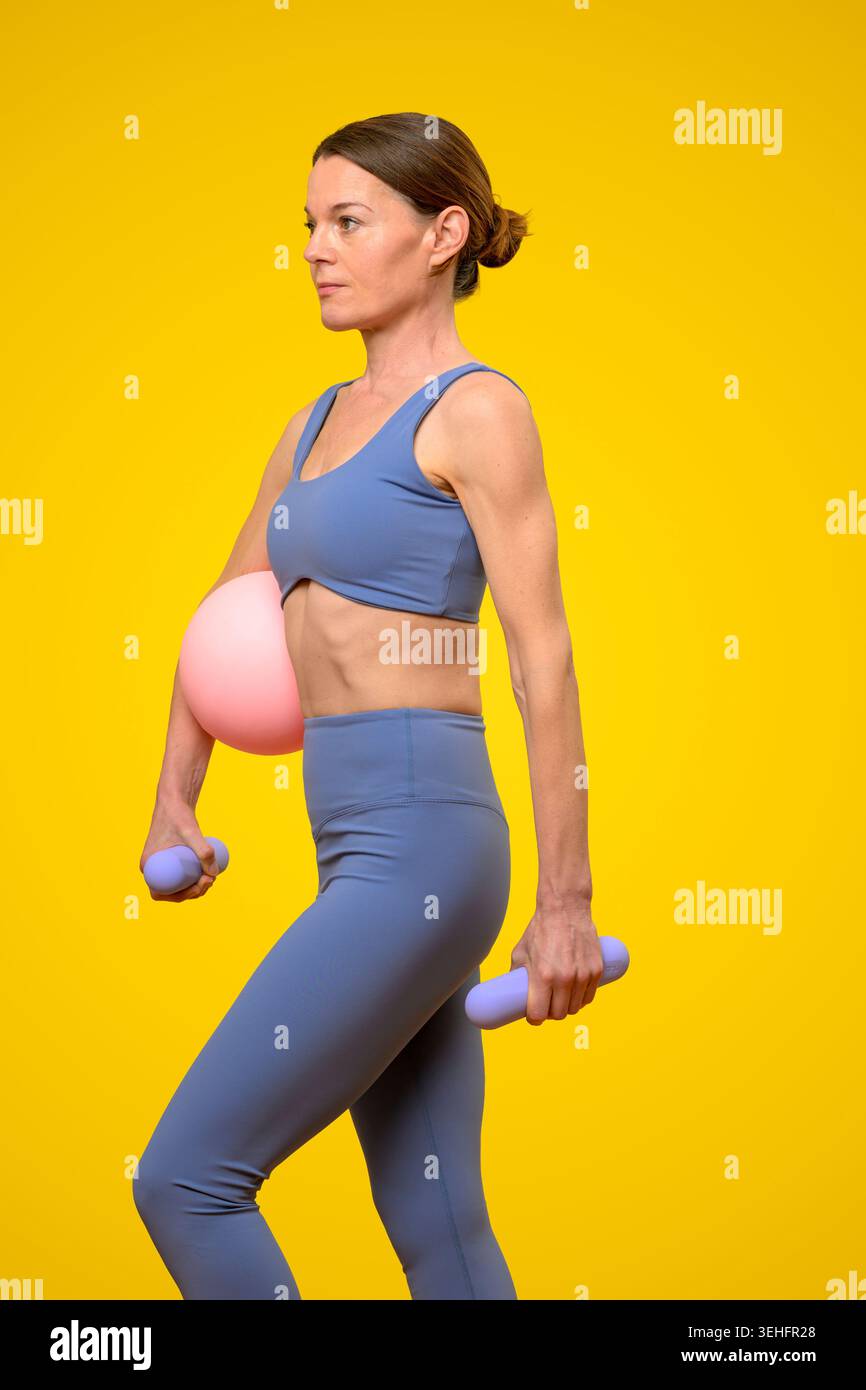 Donna che lavora con Dumbbells e Exercise Ball Foto Stock