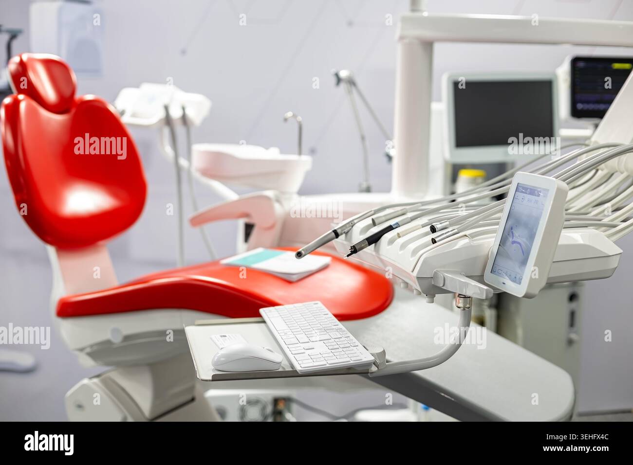 Moderna poltrona odontoiatrica con attrezzature per il trattamento. Luminoso interno della clinica odontoiatrica con sedia rossa, strumenti per il trattamento, schermo digitale e moderno Foto Stock