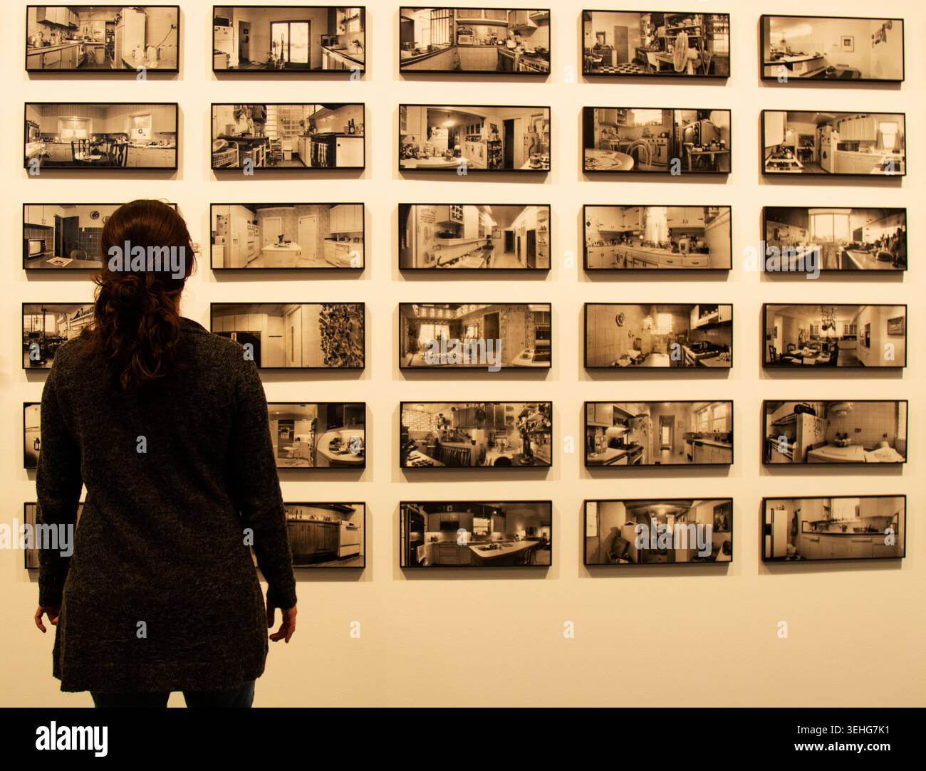 Donna in piedi nella galleria d'arte che osserva le immagini degli interni della cucina in bianco e nero Foto Stock