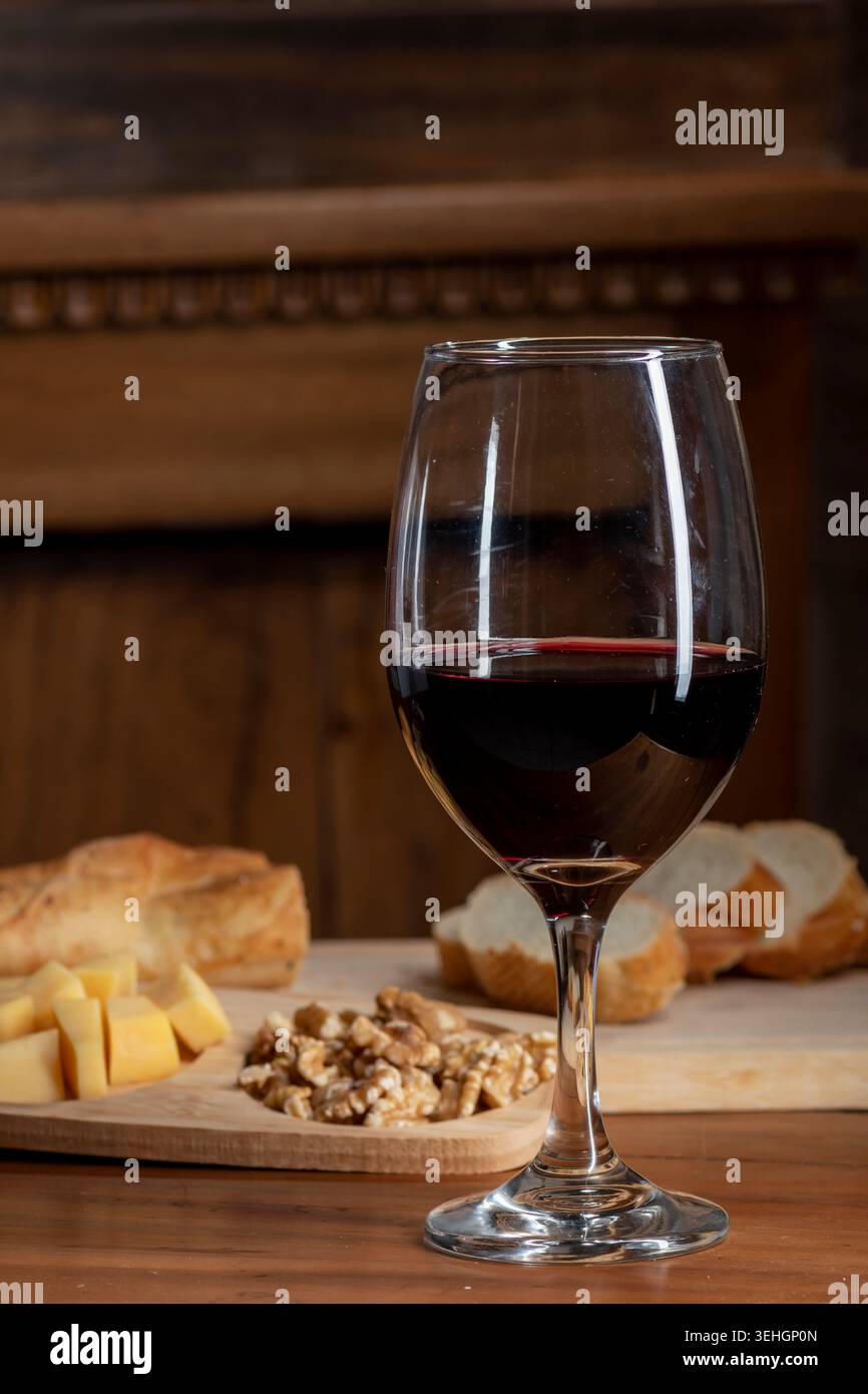 Bicchiere di vino rosso con pane e formaggio su un tavolo rustico in legno Foto Stock