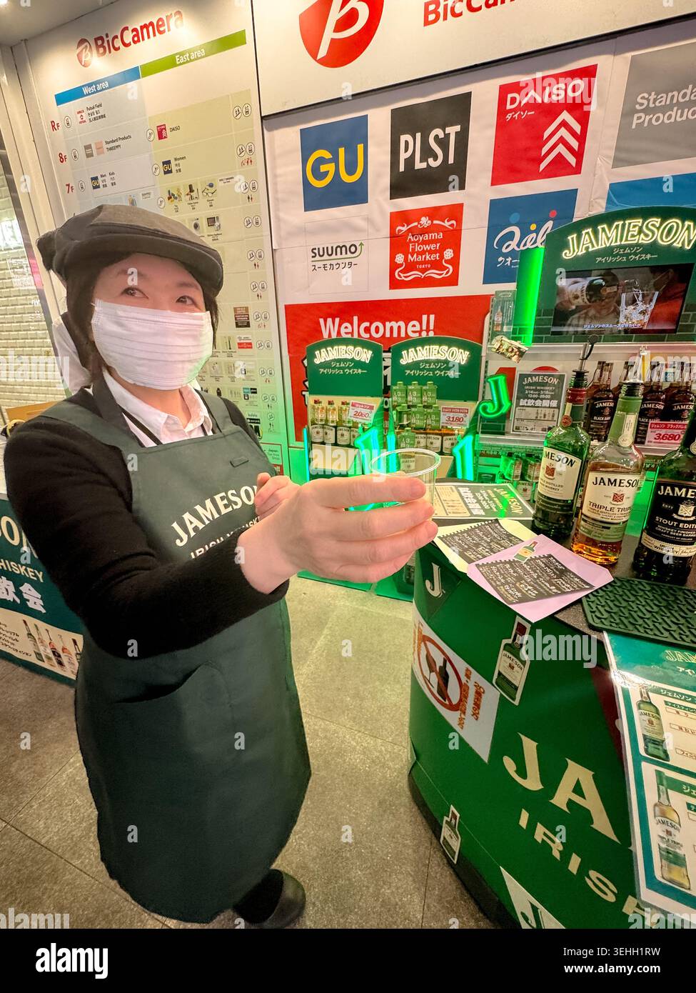 Espositore promozionale e membro del personale all'interno di un negozio al dettaglio a Shinjuku, Tokyo, Giappone. Foto Stock