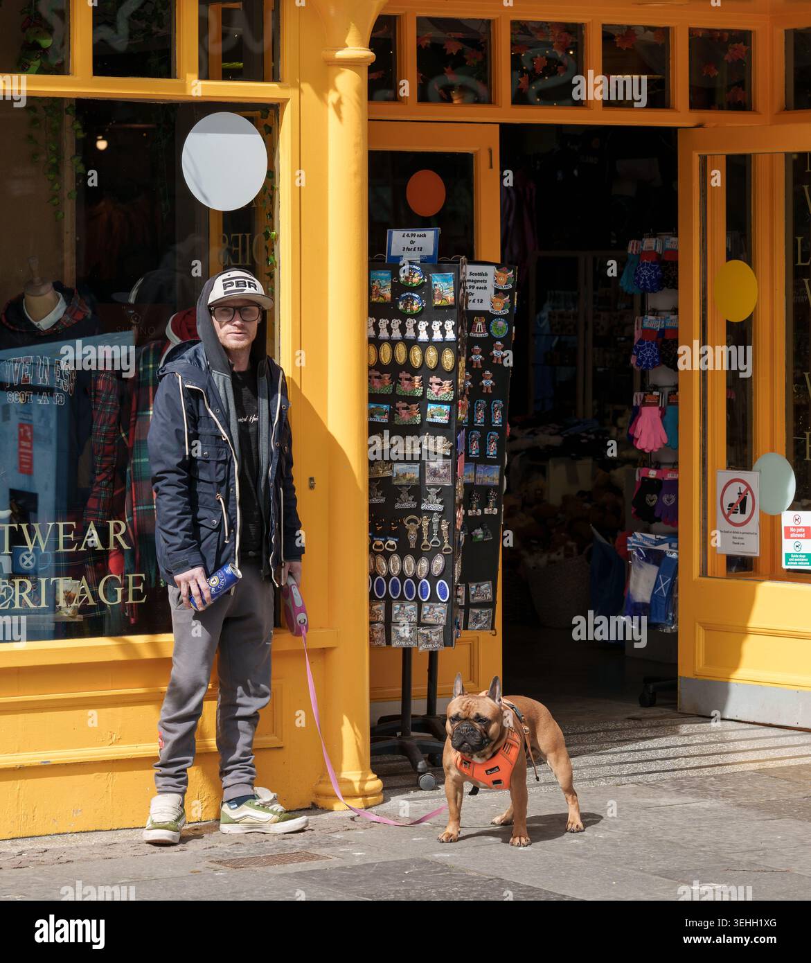 Un giovane uomo si trova con il suo cane grosso e una scatola di super lager sulla strada principale dello shopping a Inverness, Highlands e Isole, in Scozia. Foto Stock