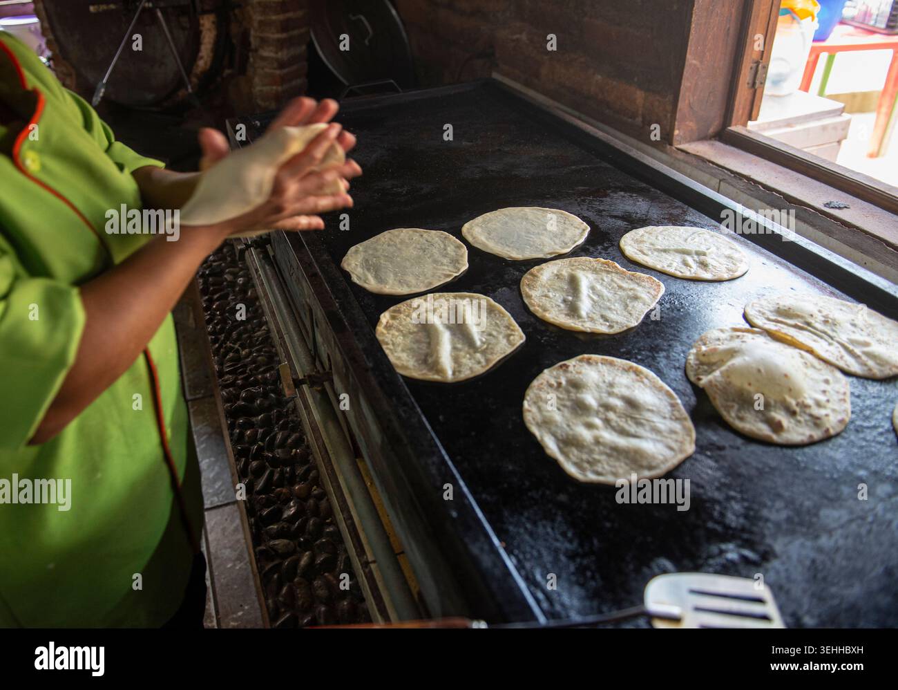 Manipolazione del cibo, le mani di una donna messicana che fa tortillas di farina in una città del Messico su una piastra accanto a una finestra, a Baja California Sur. Foto Stock
