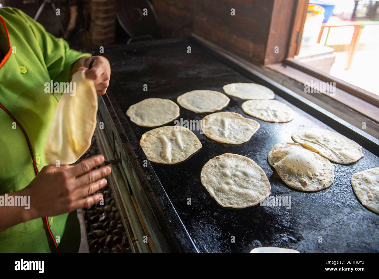 Manipolazione del cibo, le mani di una donna messicana che fa tortillas di farina in una città del Messico su una piastra accanto a una finestra, a Baja California Sur. Foto Stock