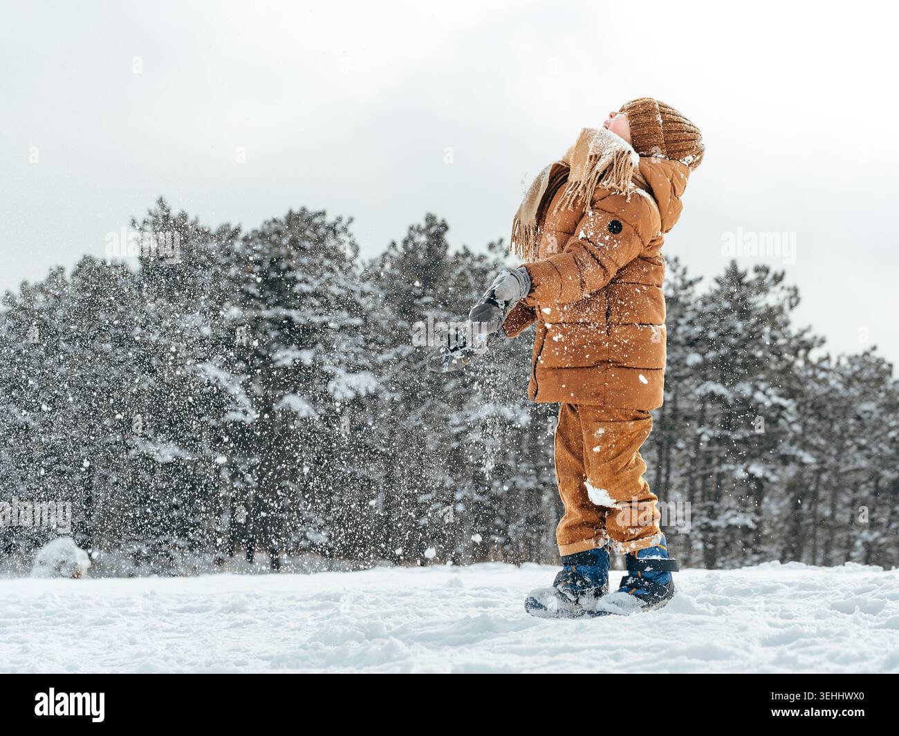 I bambini giocano sulla neve indossando abiti caldi e trascorrendo una giornata invernale all'aperto Foto Stock