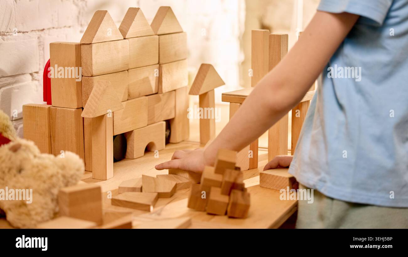 Castello in legno e bambino mano in una stanza da gioco calda. Foto Stock