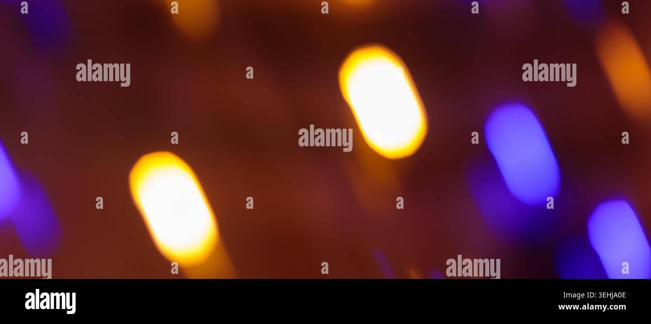 Luci bokeh astratte sfocate con luce arancione e viola su sfondo scuro per la progettazione di eventi Foto Stock
