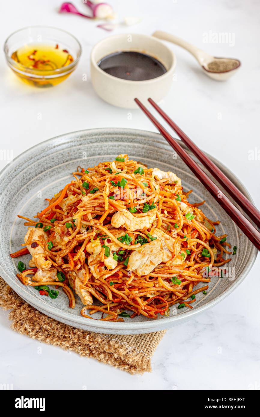 Tagliatelle speziate di hakka di pollo con bastoncini e salsa di soia Foto Stock