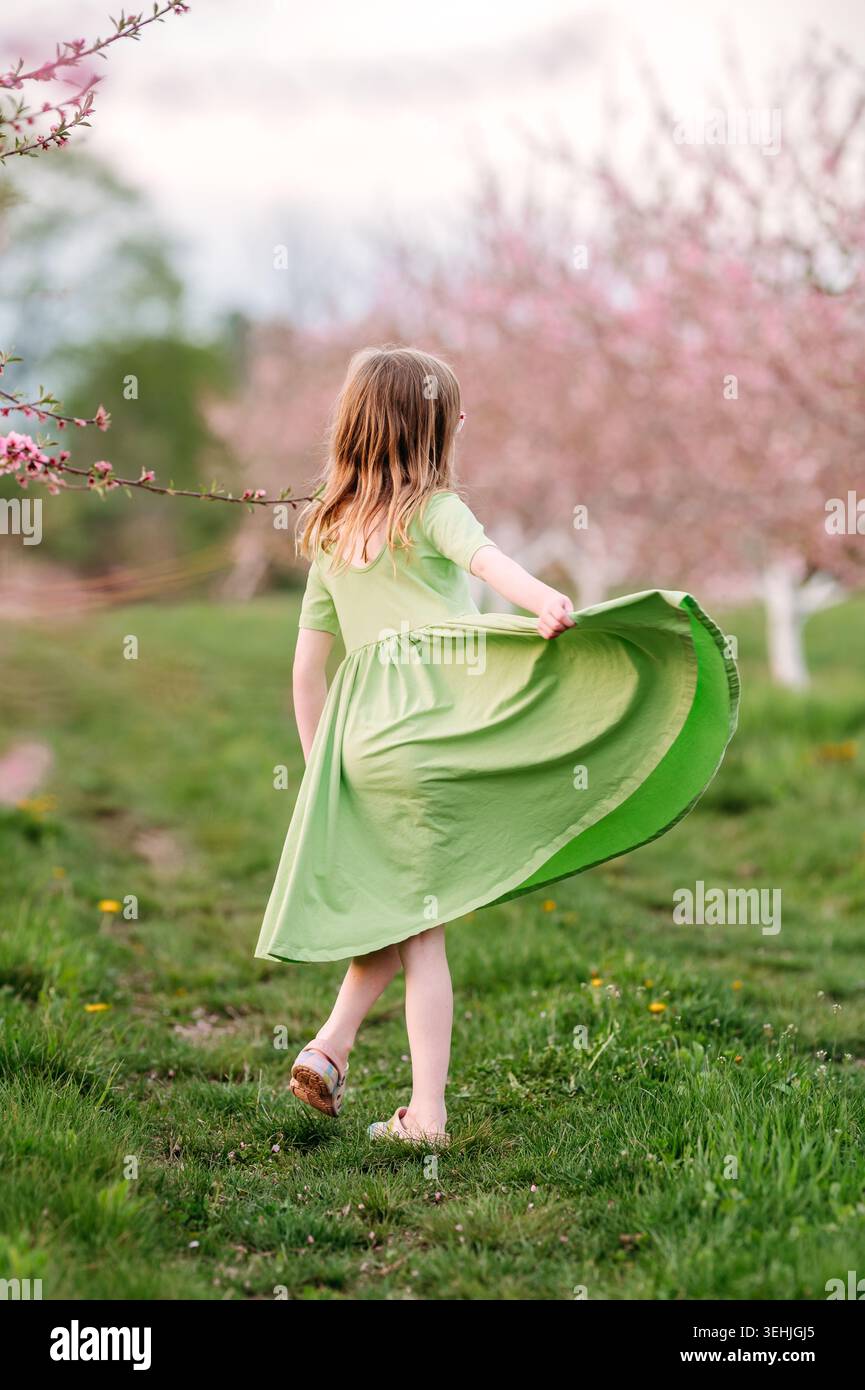 Ragazza che tiene in mano un vestito in un frutteto in fiore rosa Foto Stock